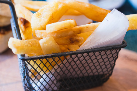 French fries in a basket on a wooden table. Selective focus.の写真素材