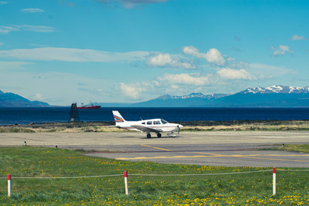 Small private plane on the runway in the airport with mountains on the background