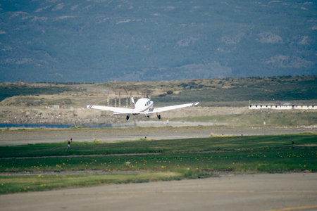 Airplane taking off from airport runway with mountains in the background.の写真素材