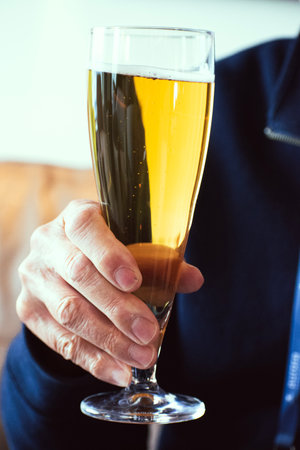 Close-up of a male hand holding a glass of champagne.の写真素材