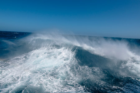 Boat wake waves in the Drake Passage, causing spray to come off   the water.