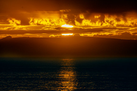 Sunset over the Beagle Channel in Argentina.  Image Has a sliver of sunlight due to the storm clouds, and there is a faint silhouette of land.の写真素材