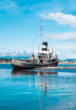 St. Christopher (formerly HMS Justice)  shipwreck with the Ushuaia harbor and Andres Mountains in the background. WWII ear ship now stands as a monument to all ships lost in the reの写真素材