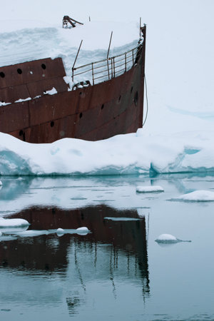 Old ship wreck in the ice with icebergs on the background.の写真素材