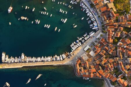 Top view of docks in Croatia with yachts and boats in summer at sunrise. Aerial footage of touristic destination in Mediterranean sea. Komiza on Vis island, Croatia in Dalmatia.の写真素材