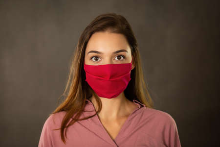 Alert girl with protective face mask on looking into camera from front view. Head of woman with...