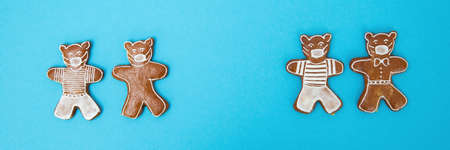 Gingerbread bears with surgical mask on turquoise background. Traditional easter biscuits with ...