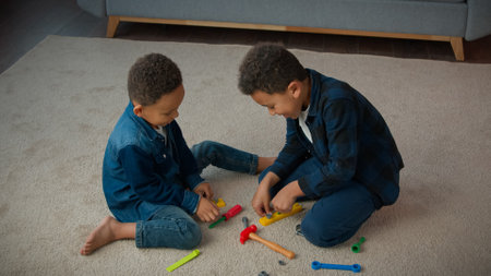 Ethnic African American multiracial multiethnic boys kids schoolboys pupils sons indoors at home children brothers cousins friends on floor carpet play with toys tools playing repair game togetherの写真素材