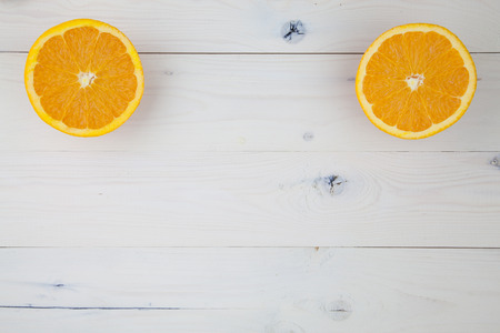 Two cut orange halves lying on a white wooden table.の写真素材