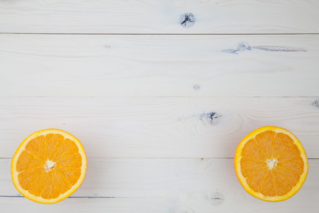 Two cut orange halves lying on a white wooden table.の写真素材