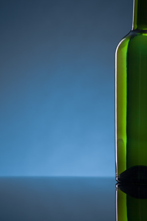 Bottle on the right side on a glossy surface. With blue background. Wine list concept.の写真素材