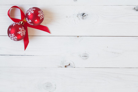 Christamas balls and a red ribbon on a white wooden backgroundの写真素材