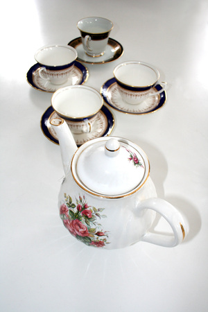 Fine China teapot and teacups on saucers sitting on a white table.の写真素材