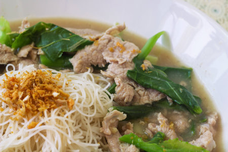 vermicelli  noodles topped with pork and kale
