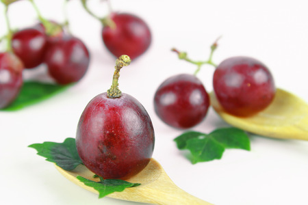 Ripe red grape with leaves isolated on whiteの写真素材