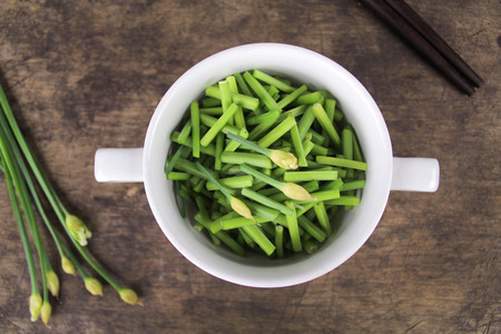 bunch of fresh chives on a wooden cutting boardの写真素材
