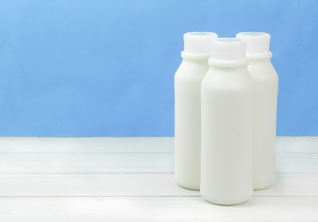 A bottle of milk and glass of milk on a wooden table on a  backgroundの写真素材