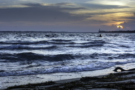 Ocean waves lapping at the shore with the sunset in the distanceのeditorial素材