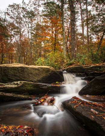 Portrait format of long exposure shot of the beautiful Cheaha Falls with bright autumn color in the background.の写真素材