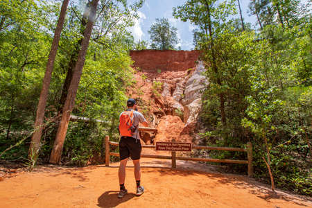 Lumpkin, Georgia, USA- June 6, 2021: A male hiker taking cell phone photos in one of the canyons at Providence Canyon State Park in southwest Georgia.のeditorial素材