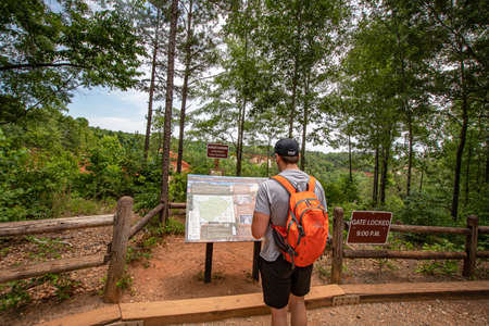 Lumpkin, Georgia, USA- June 6, 2021: A male hiker examines the trail map at Providence Canyon State...