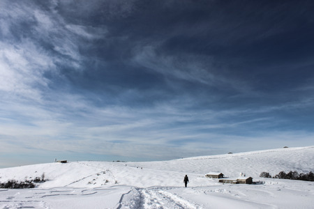 Person walking in a snowy plateau at winterの写真素材