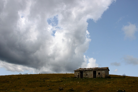 Old abandoned hut at the top of a hill in a blue skyの写真素材