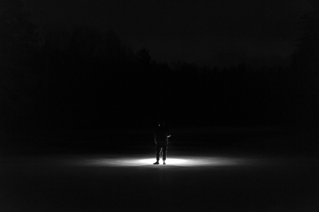 Man with flashlight at night in black and white. Standing on ice lake in Sweden Scandinavia Europe. Monochrome fine art.の写真素材