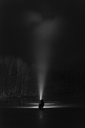 Man with flashlight at night in black and white. Standing on ice lake in Sweden Scandinavia Europe. Monochrome fine art.の写真素材