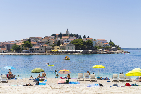 Primosten, Croatia, August 5 2017, People sunbathing on beautiful beach, Nice warm summer day with blue sky and ocean.のeditorial素材