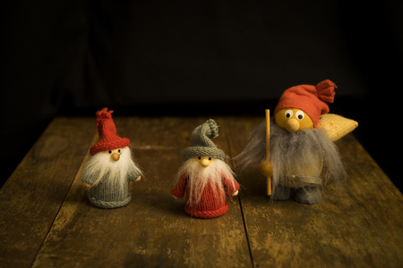 Three small Santa Claus standing on wooden table with black background looking forward, Nice and...