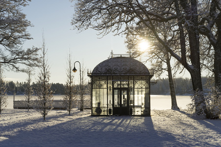 Beautiful nature and landscape photo of cold sunny winter day in Sweden Scandinavia. Nice clear blue sky at morning. Snow, small glass house and ice lake. Calm, peaceful and happy outdoors image.の写真素材