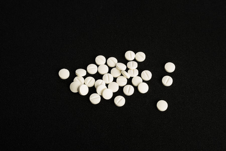 White medicine tablets isolated on black background cloth. Painkiller pills for medical treatment....