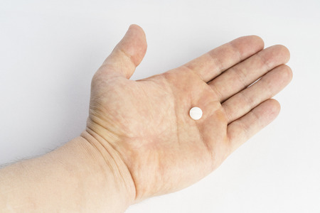 Open hand with one medicine tablet isolated on white background. Painkiller pill for medical treatment. Drug against illness and sickness.の写真素材