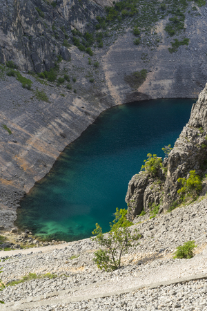 Blue Lake Imotski Croatia, Beautiful nature and landscape photo of very big,  deep sinkhole in Dalmatian mountains. Nice sunny summer day. Water, rocks and stones. Amazing place to visit on vacation.の写真素材