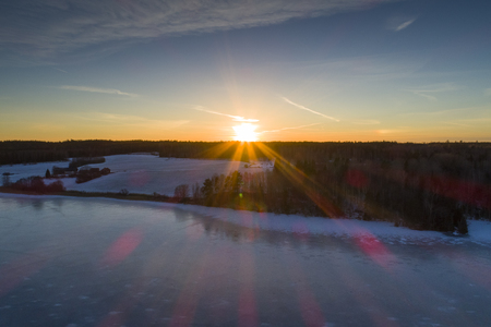 Beautiful nature and landscape at cold winter evening in Sweden Scandinavia Europe. Nice sunset and frozen ice lake. Shot with drone from above in sky. Calm, peaceful and happy outdoor image.の写真素材