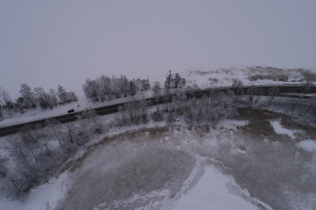 Beautiful aerial photo of frozen ice lake and road in Sweden, Scandinavia. Nice nature and landscape on winter dusk evening. Lovely outdoors at sunset shoot with drone from above in sky.の写真素材