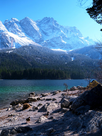 Majestic snow-capped mountains reflect in the tranquil lake during a sunny winter dayの写真素材