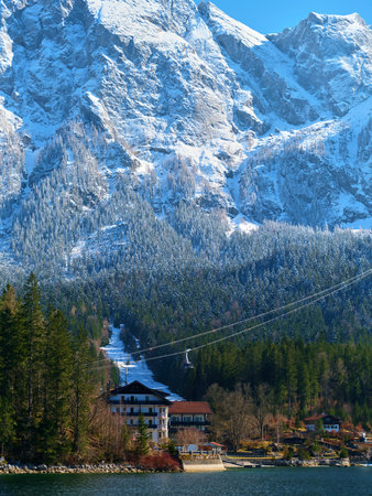 Stunning winter landscape featuring snow-capped mountains and a scenic lake beneath a clear blue skyの写真素材