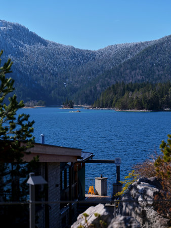 Snow-capped mountains and serene lake viewed from a cozy lodge on a clear winter dayの写真素材