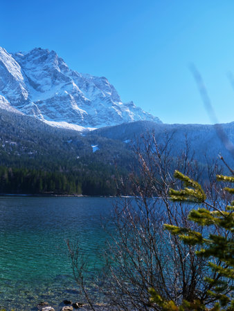 Scenic mountain lake surrounded by snow-capped peaks with clear blue sky on a bright sunny dayの写真素材