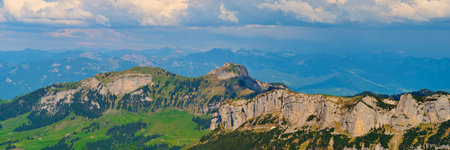 Scenic view of mountain peaks under a partly cloudy sky in the Swiss Alps during the summer seasonの写真素材