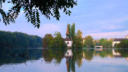 Scenic lake view with church and reflection during calm sunrise in a serene park setting