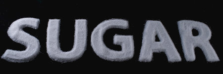 White sugar arranged in bold letters on a dark background in a creative kitchen settingの写真素材