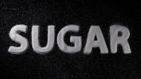 Sugar spelled out with white granules on a dark surface showcasing the texture and contrast of the materialの写真素材