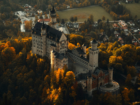 Bavarian castle stands among autumn trees as golden leaves cover the landscape in the late afternoon lightの写真素材