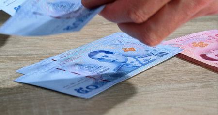 Counting and organizing banknotes on a wooden table during a financial transaction