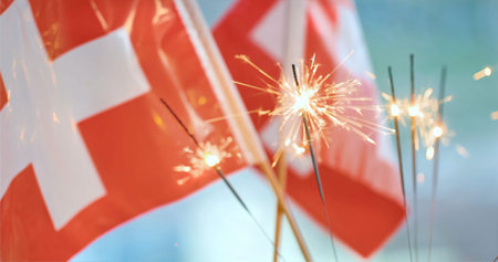 Swiss flags wave as sparklers light up the space during a celebration in a festive setting in...
