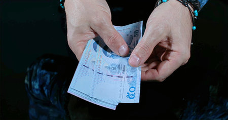 Closeup Of Hands Sorting Banknotes At Night, Freelancer Inspecting Bills In Lowlit Setting