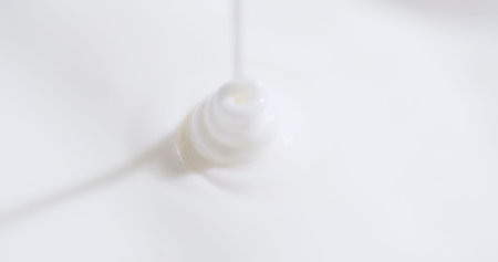 Action of pouring liquid from a plastic bottle onto a white surface for various uses and purposes in a kitchen or laboratoryの写真素材